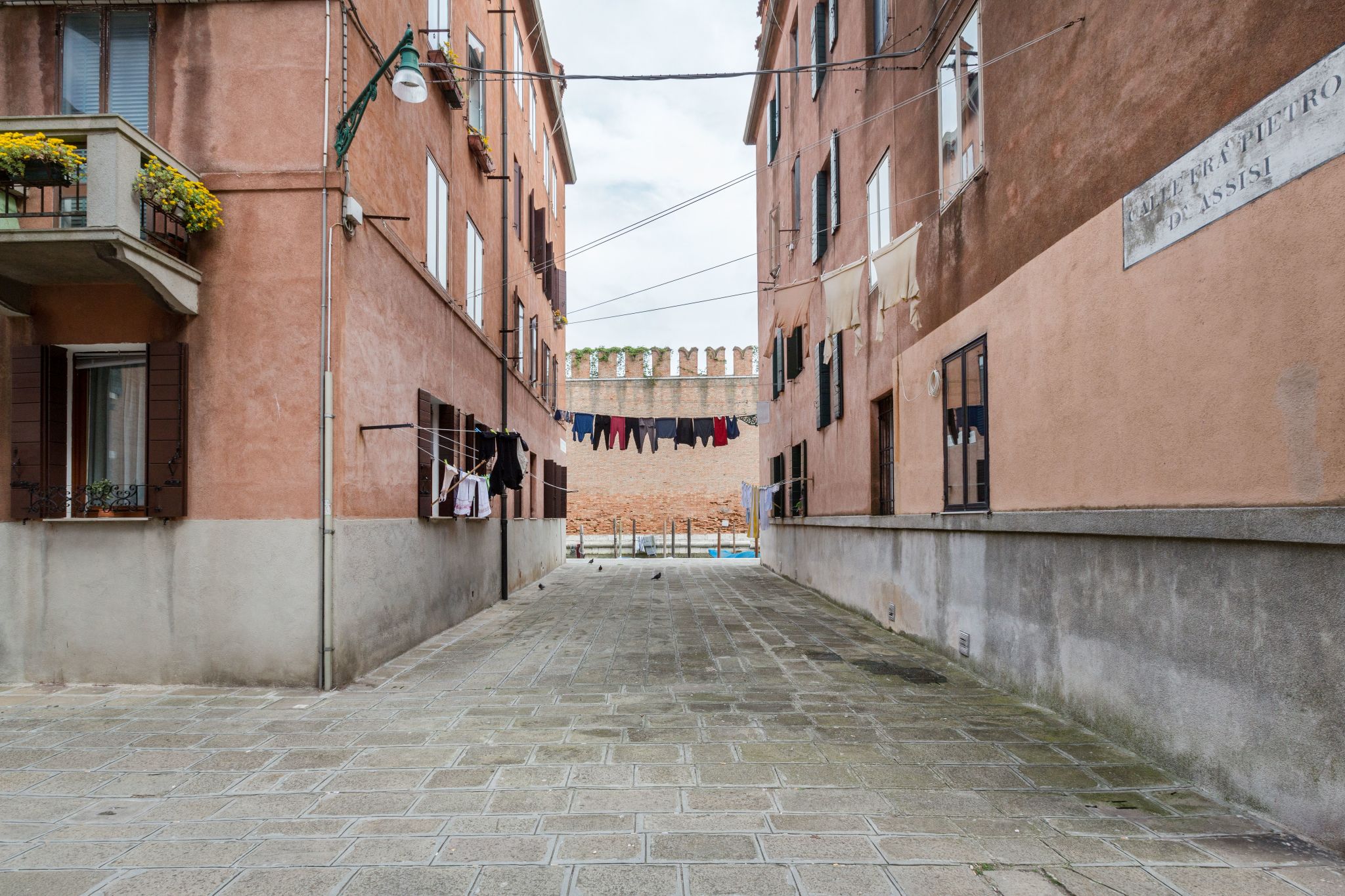 Calle di Venezia, abiti colorati stesi su fili che passano da un edificio con finestre all'altro, Veneto